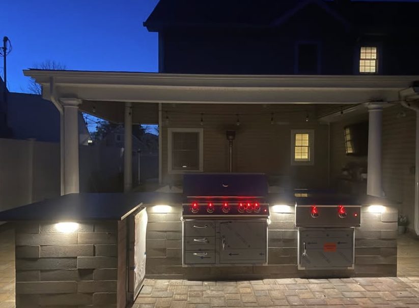 Covered outdoor kitchen patio with accent lighting at dusk