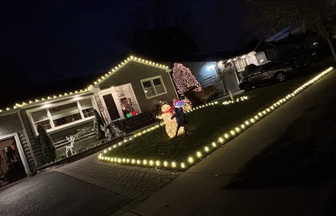 Long Island home with warm white holiday roofline lights, a lit front lawn border, wrapped tree and lit snowman and reindeer displays